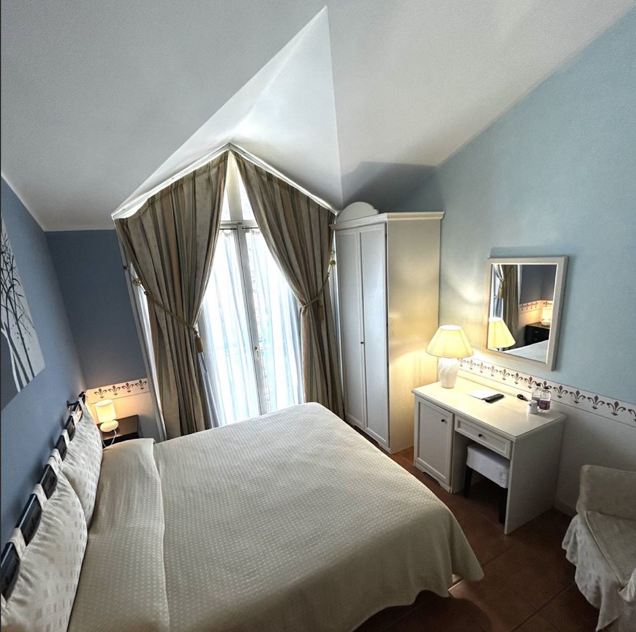 Cottage Room: a large bed under a pitched ceiling, blue walls.