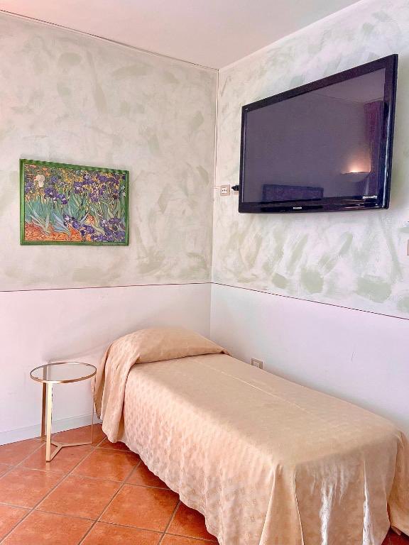 Single Room: a single bed against soft green walls, a framed print of irises.