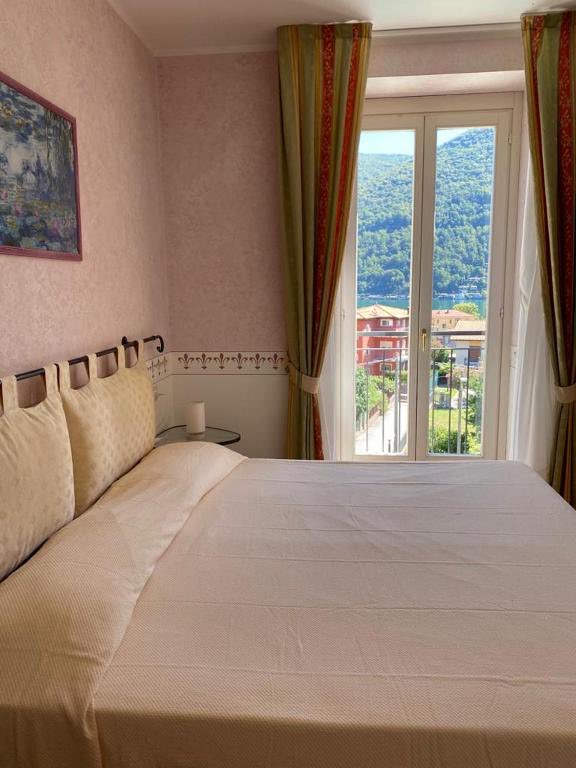 Superior Room: a pink room with a double bed and an open French window onto the hills.