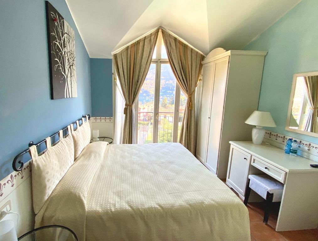 Una camera blu in mansarda: un letto matrimoniale sotto il soffitto spiovente, lunghe tende alla finestra.