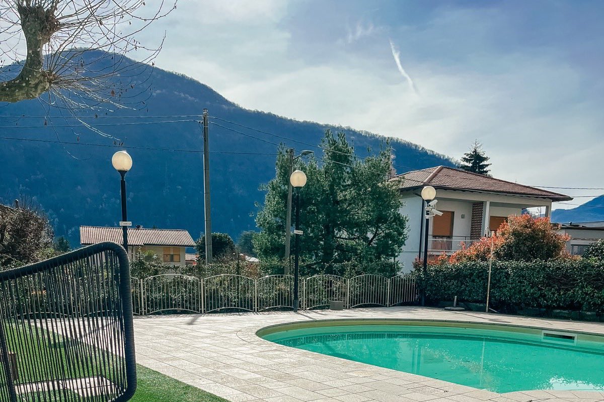 A garden armchair and a small breakfast table beside the pool, the mountains behind.