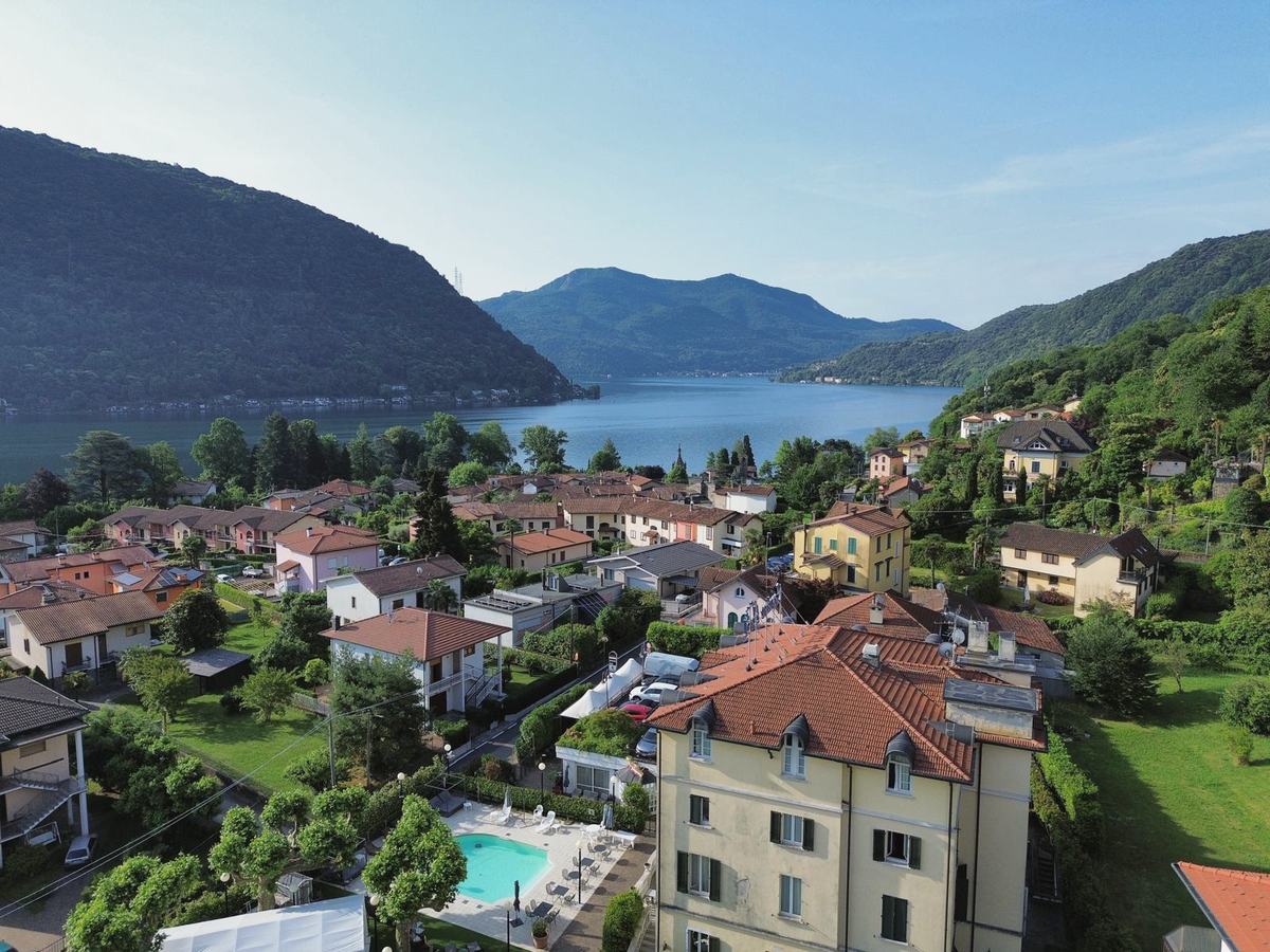 Brusimpiano from the air: the hotel and its courtyard pool, the village roofs and Lake Lugano beyond