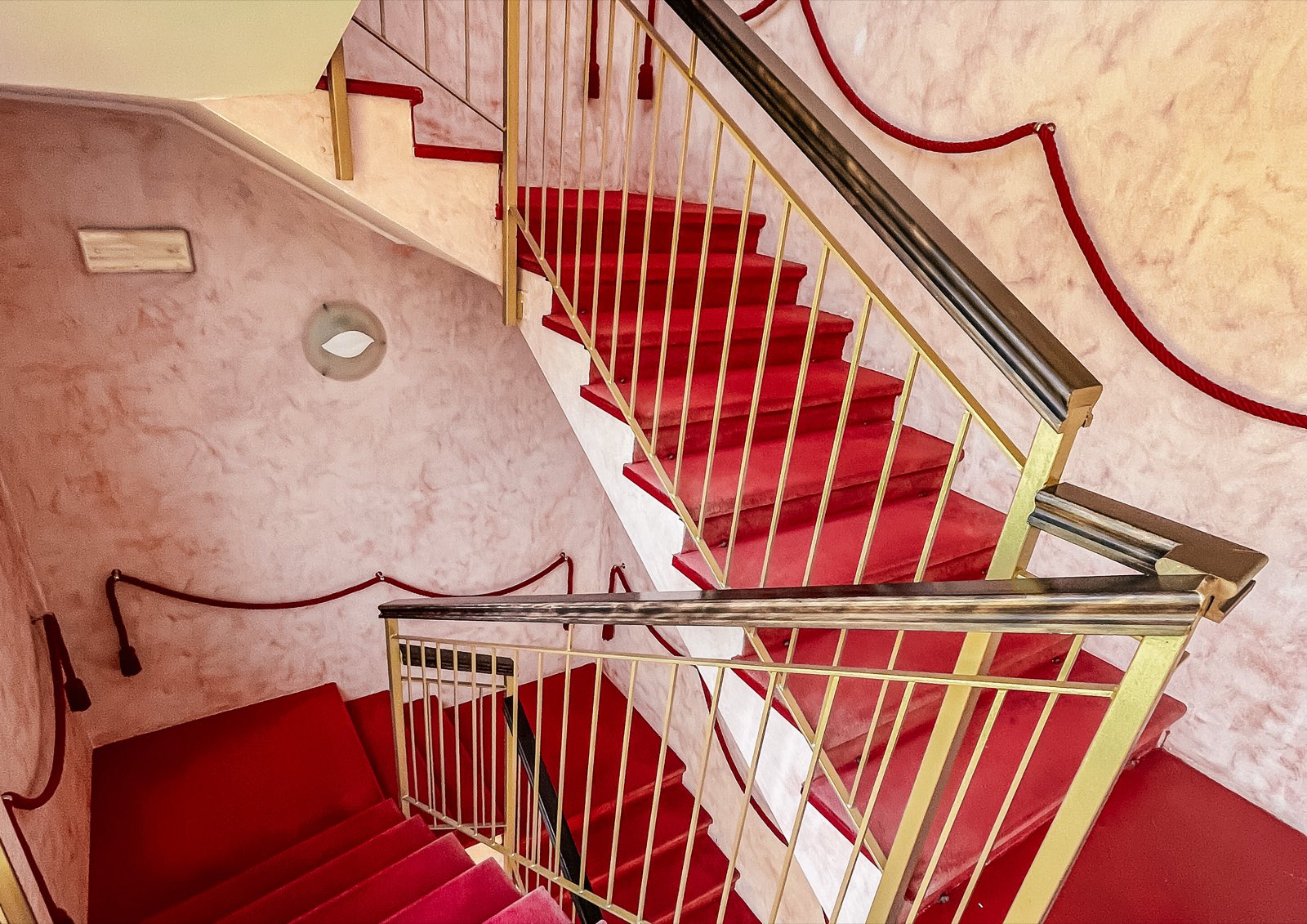 A red-carpeted staircase with brass railings.